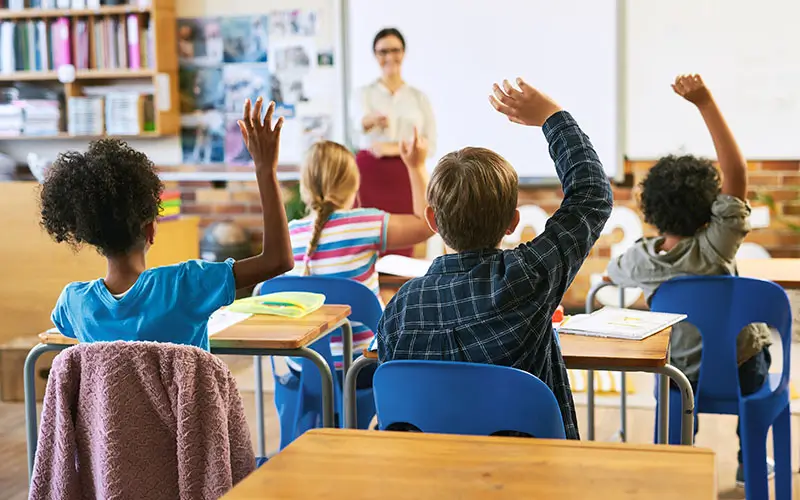 classroom full of students raising their hands